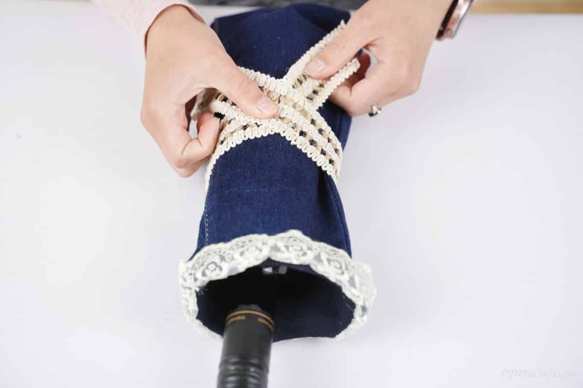 hand wrapping lace around middle of denim wine bottle cover