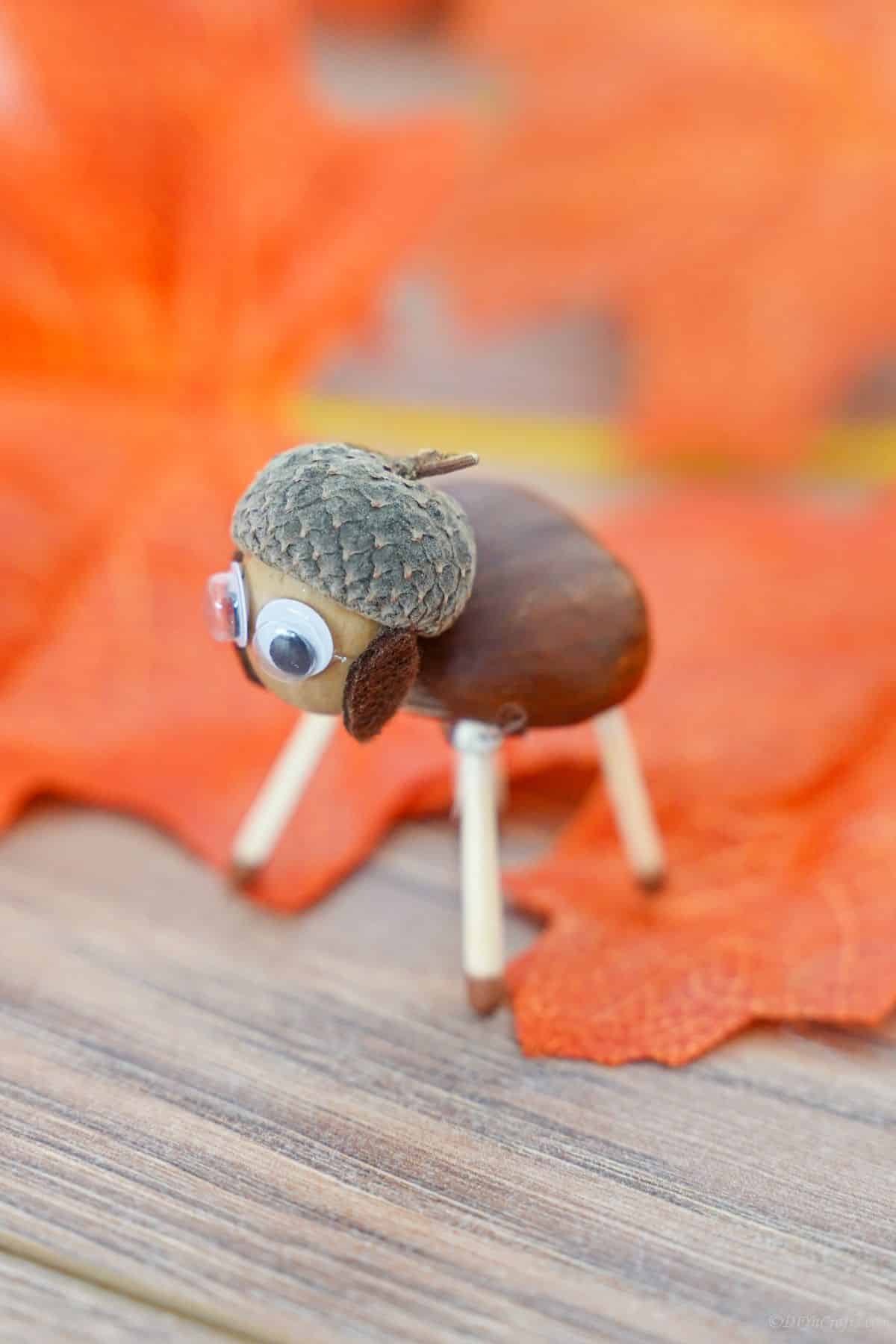 match stick legs on acorn sheep on table with fake leaves