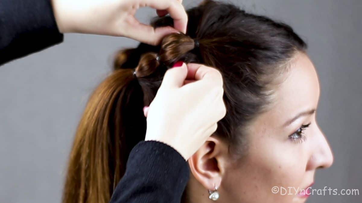 hands fluffing braid on side of brunettes head