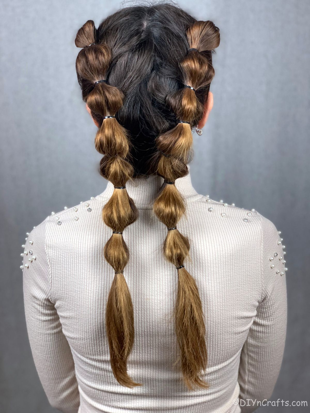 back of bubble braids on woman with brown hair in white shirt