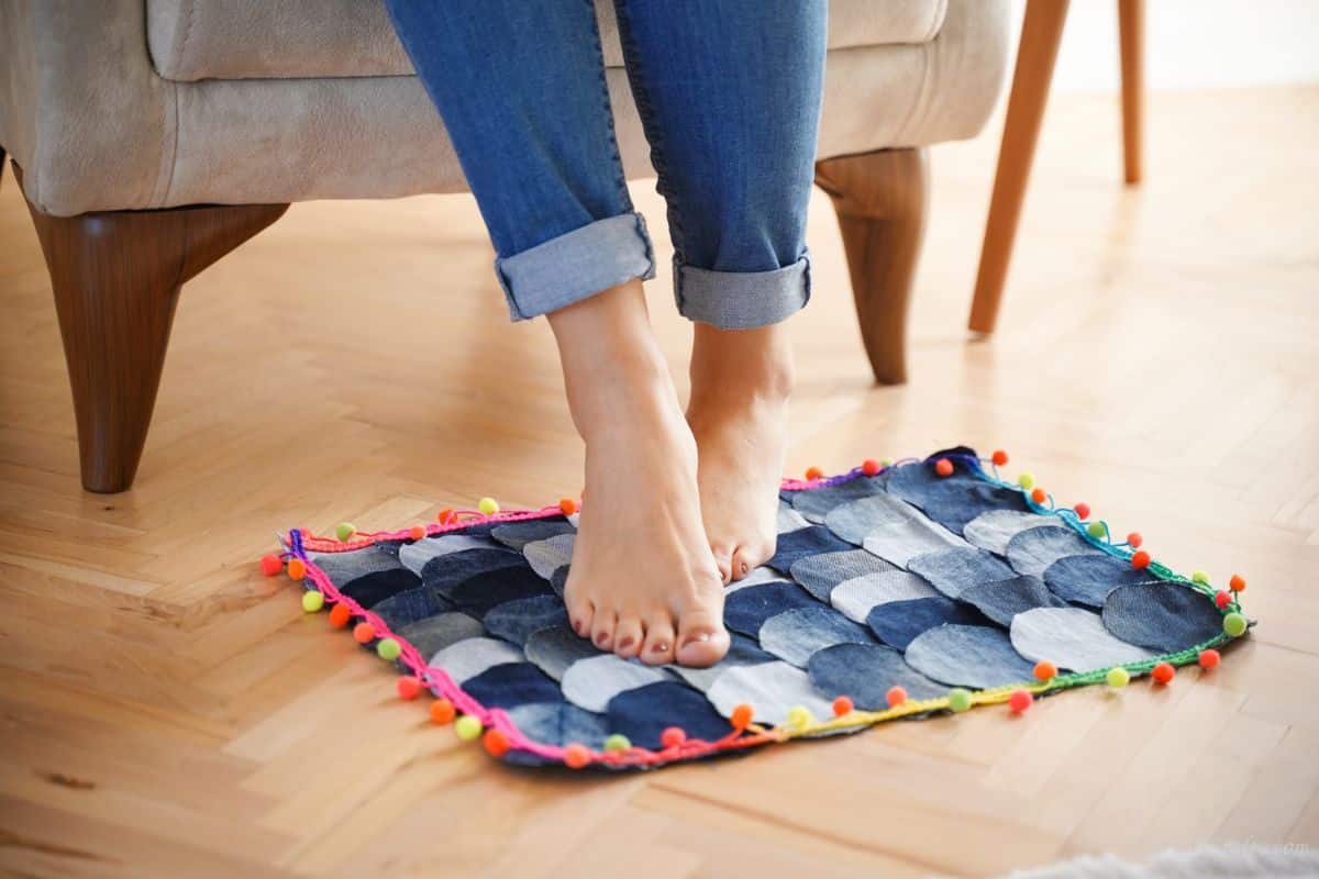 feet sitting on top of denim floor rug by chair