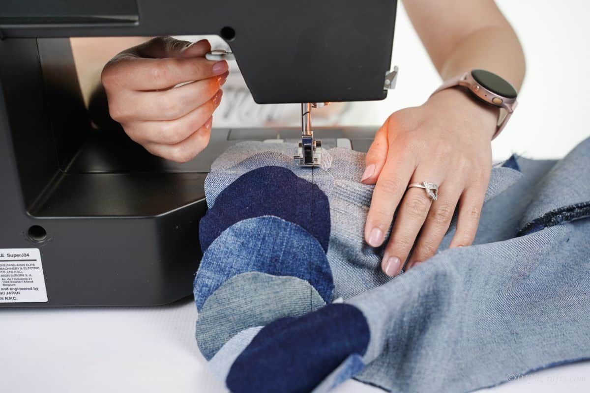 black sewing machine being used to sew denim