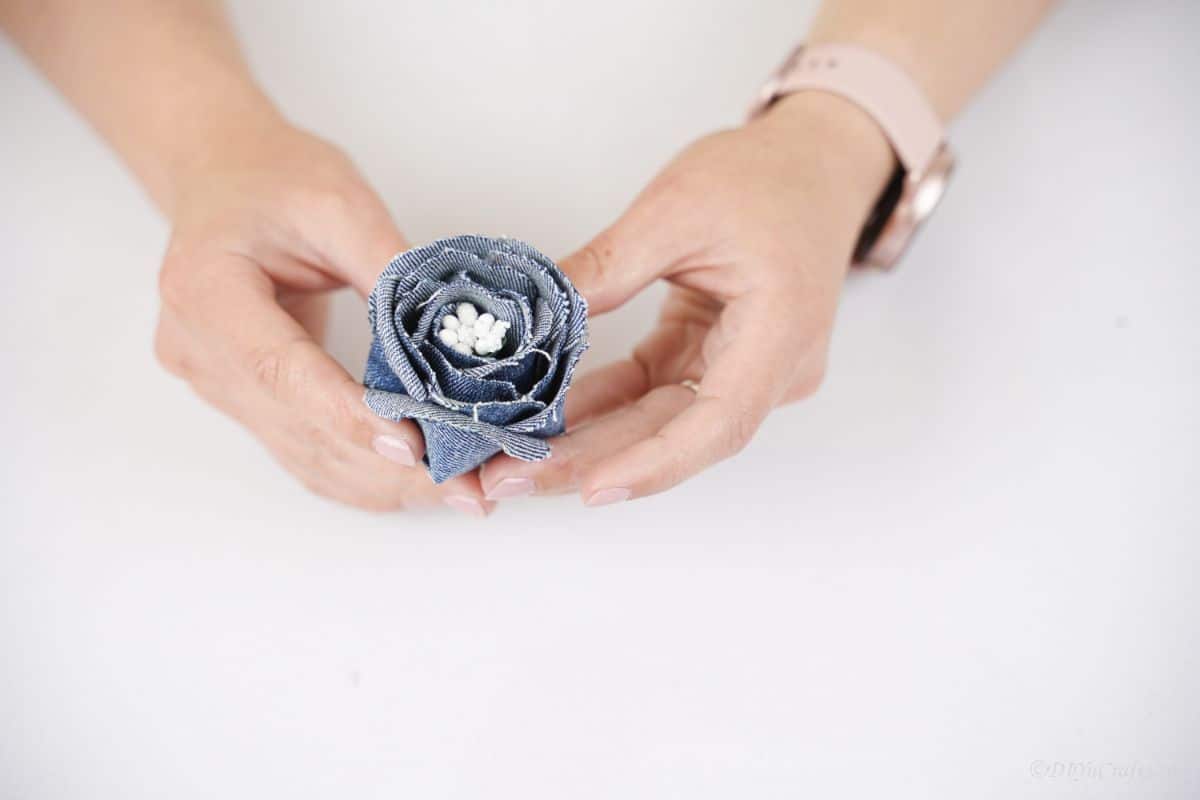 hands holding denim flower with white center