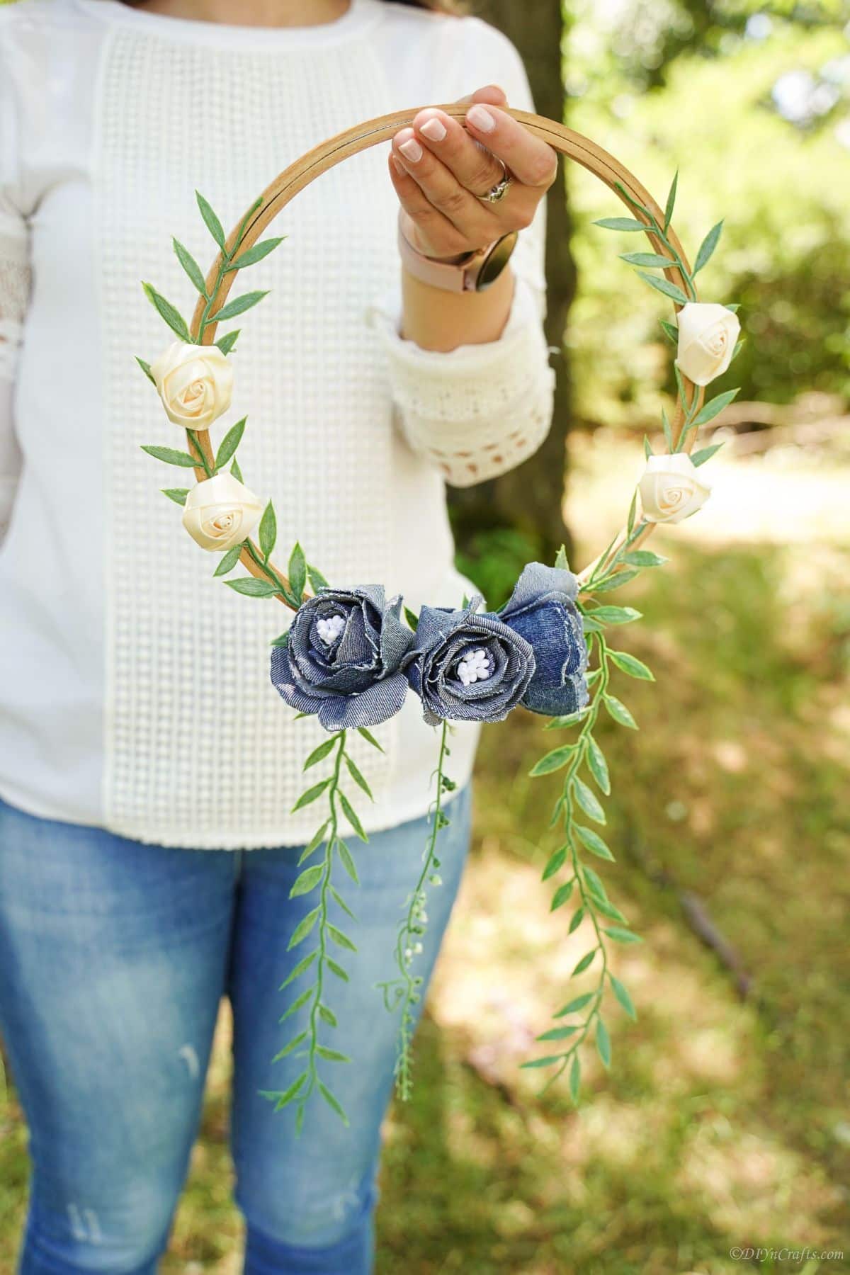 woman in denim and white holding denim floral wreath in front of her