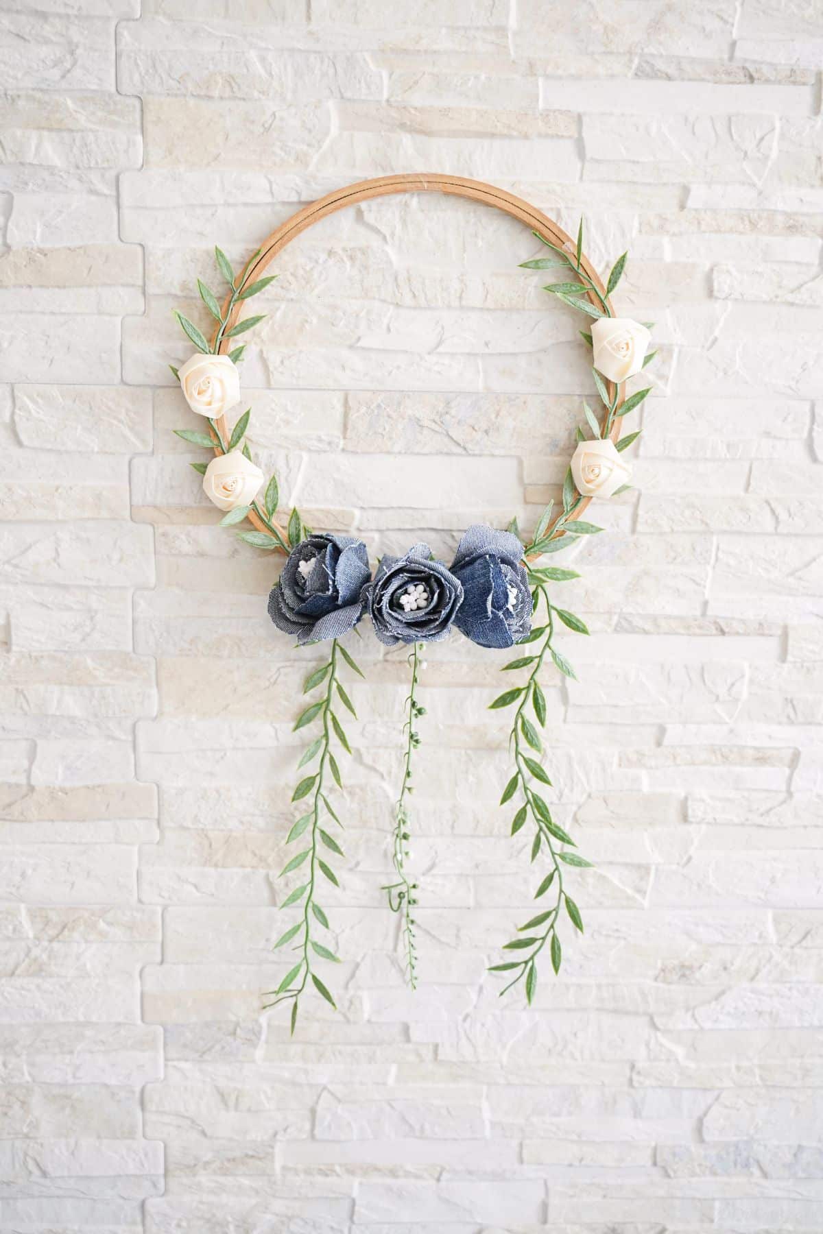 embroidery hoop wreath hanging on white brick wall