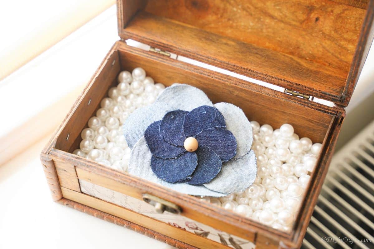 denim flower applique on top of fake pearls in wood box