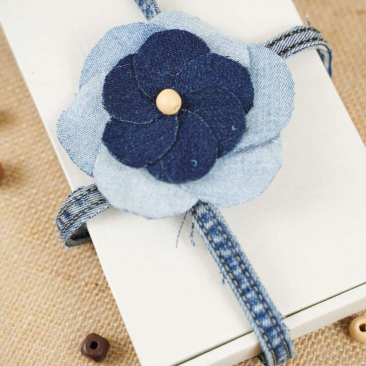 rectangle white box on brown table with denim flower as a bow