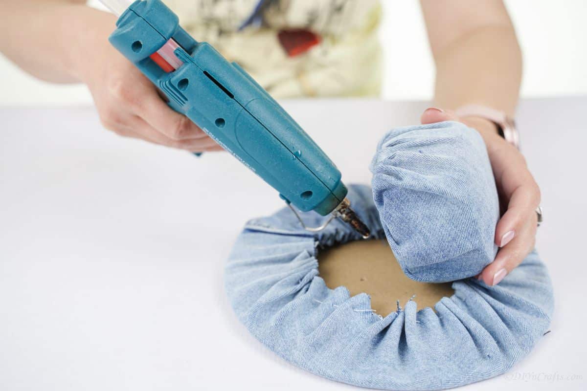 blue hot glue gun being used to connect denim pieces