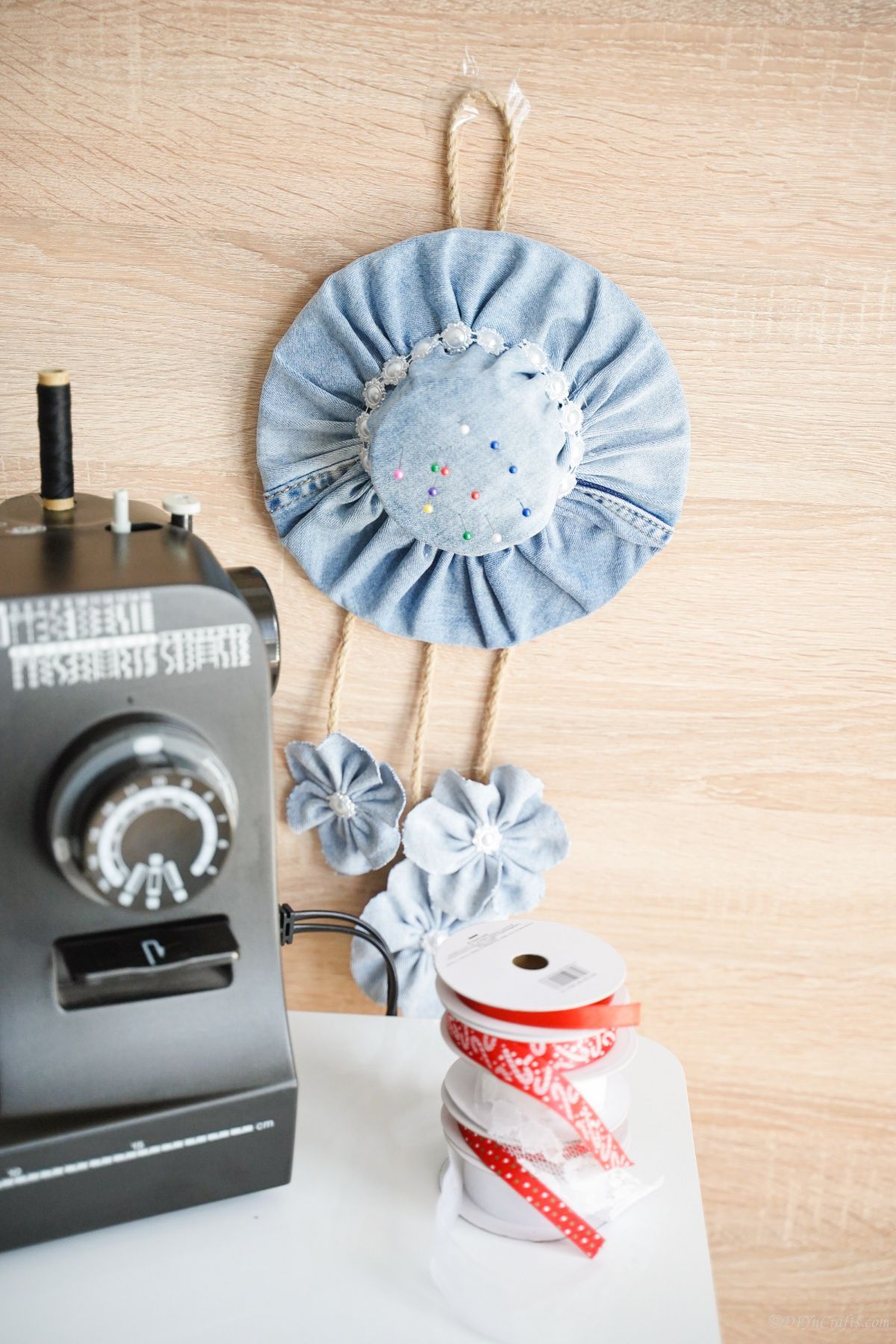 denim pin cushion hanging on wall by sewing machine table