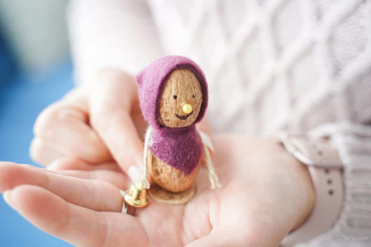 lady in white sweater holding purple walnut mouse in her hand