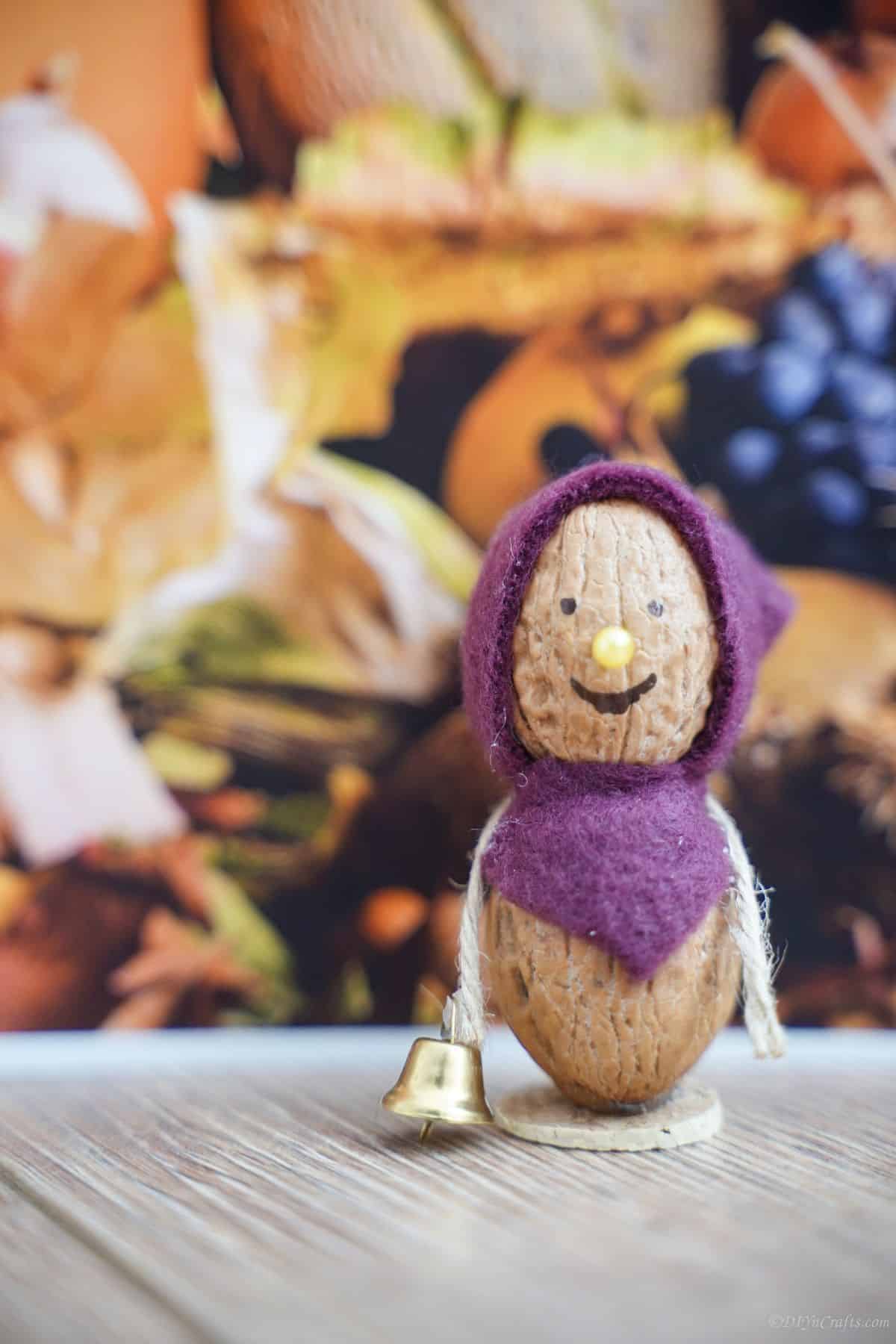 purple bonnet on walnut mouse sitting on table in front of fall paper background
