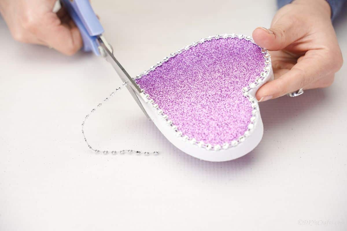 purple and white heart lid having ribbon trimmed with gray scissors