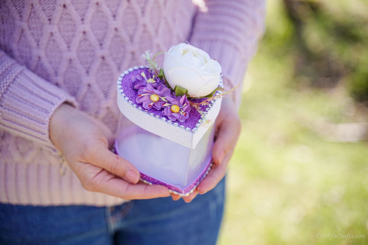 woman holding purple and white heart box