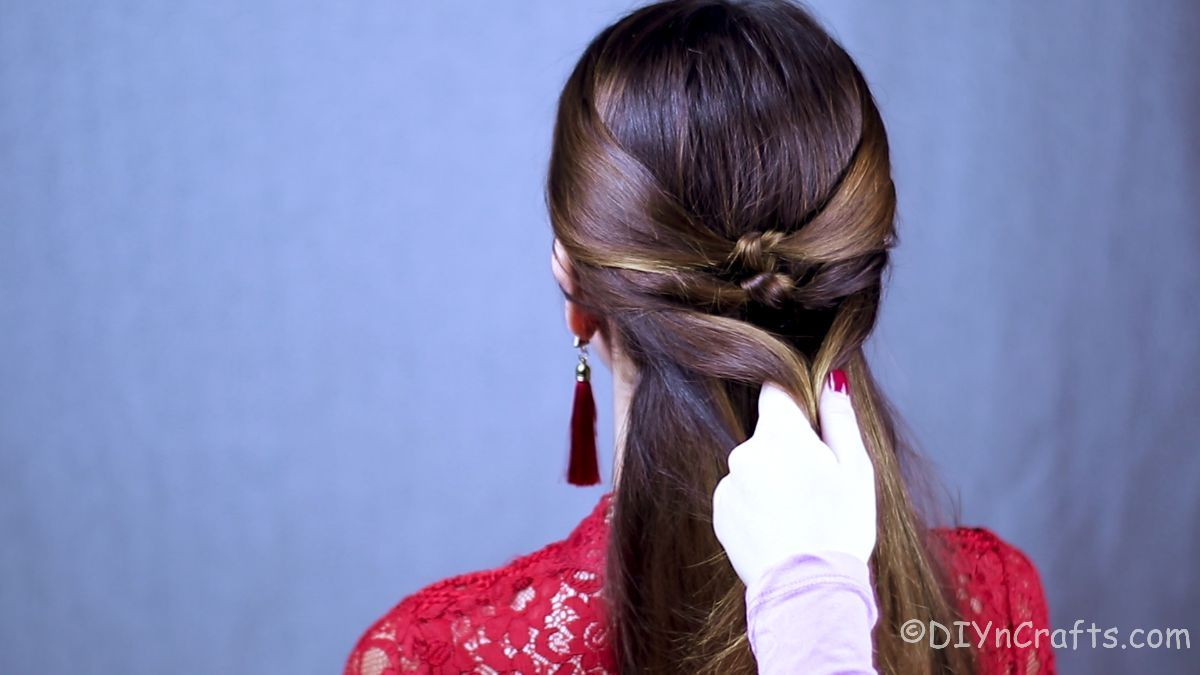 hand braiding hair of woman in red shirt