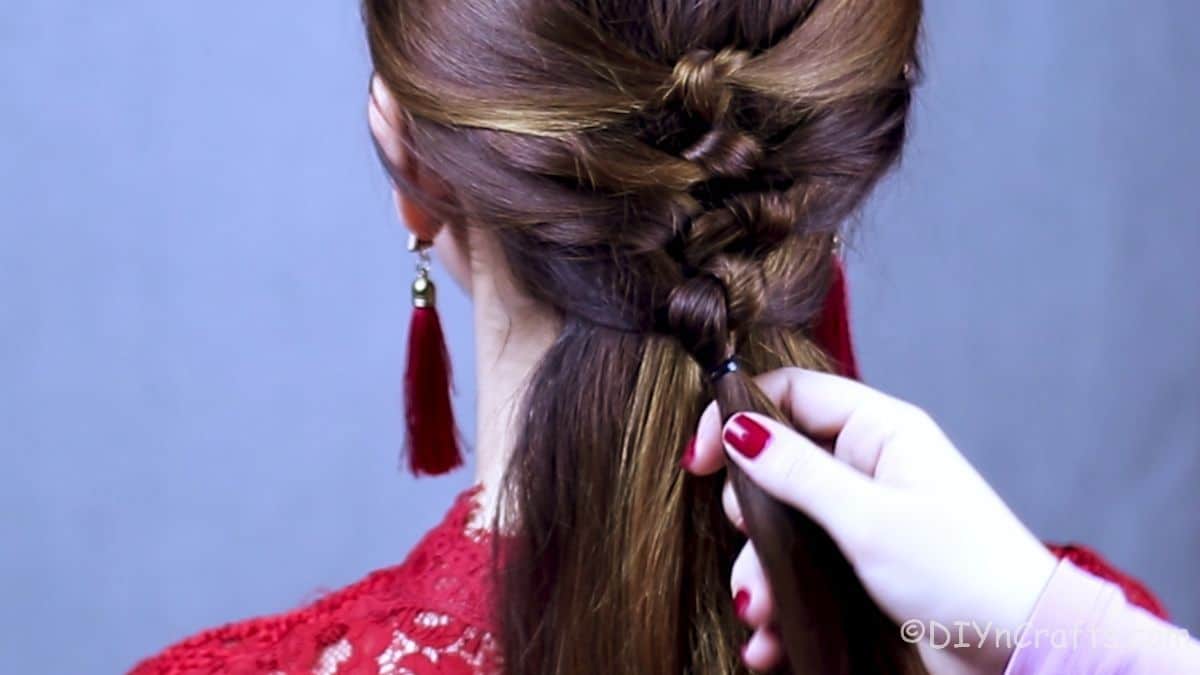 knot braids being added to brown hair on woman in red