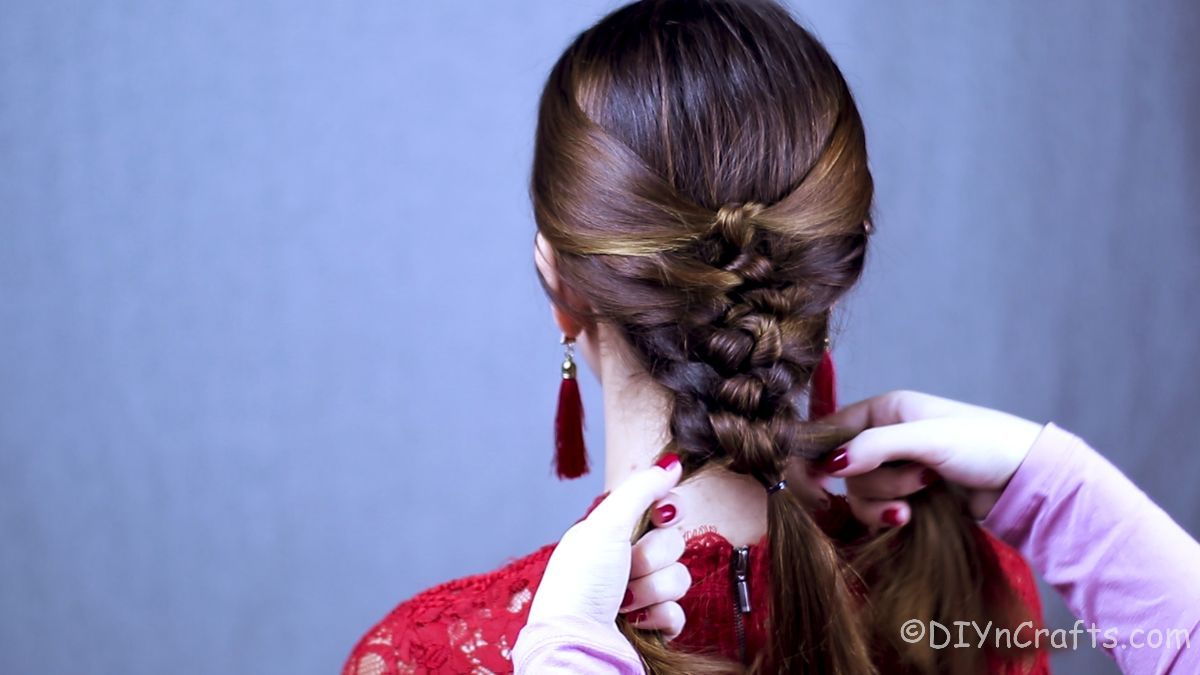 hair being braided on woman in red lace top