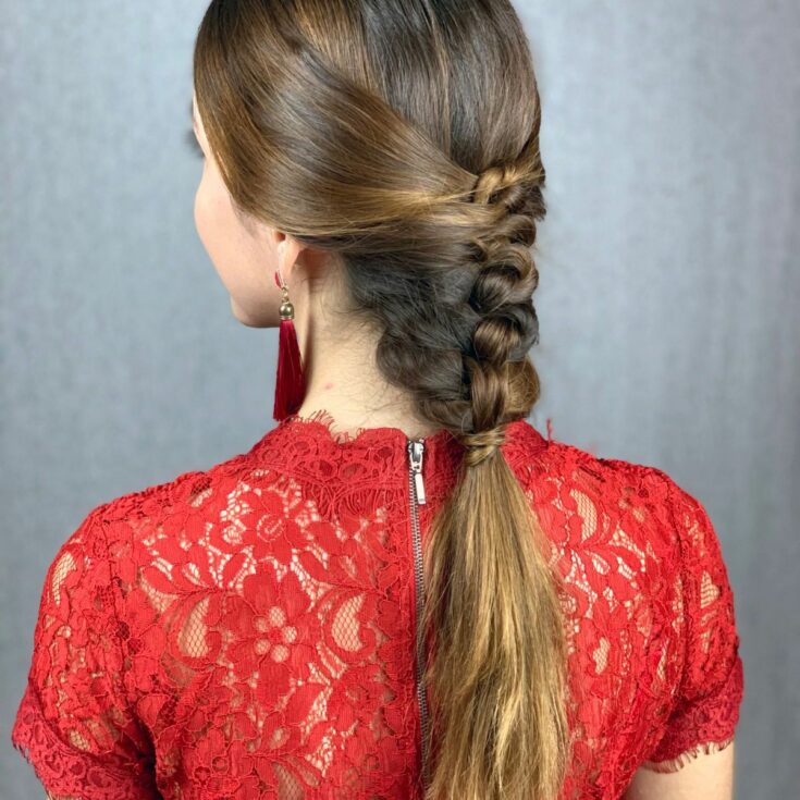 woman in red with braided hair and tassel earrings facing away from camera