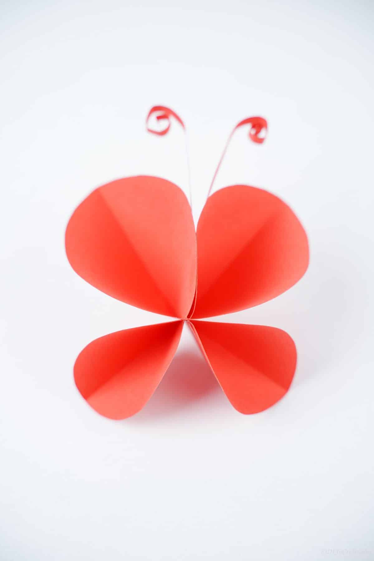 white background behind red paper butterfly