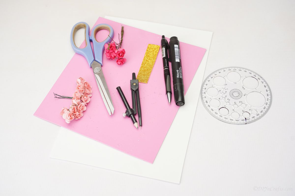 pink adn white paper with pens and scissors on white table