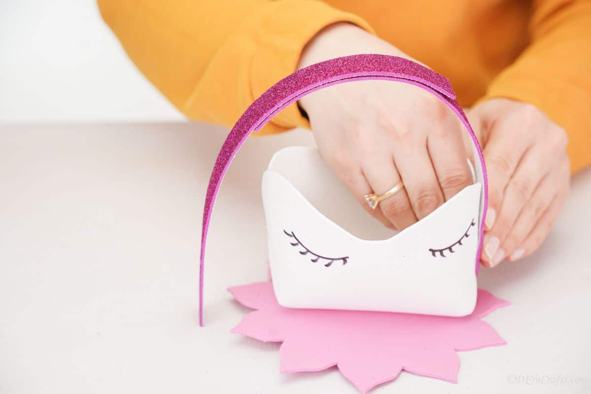 hand holding pink glitter paper on side of unicorn basket
