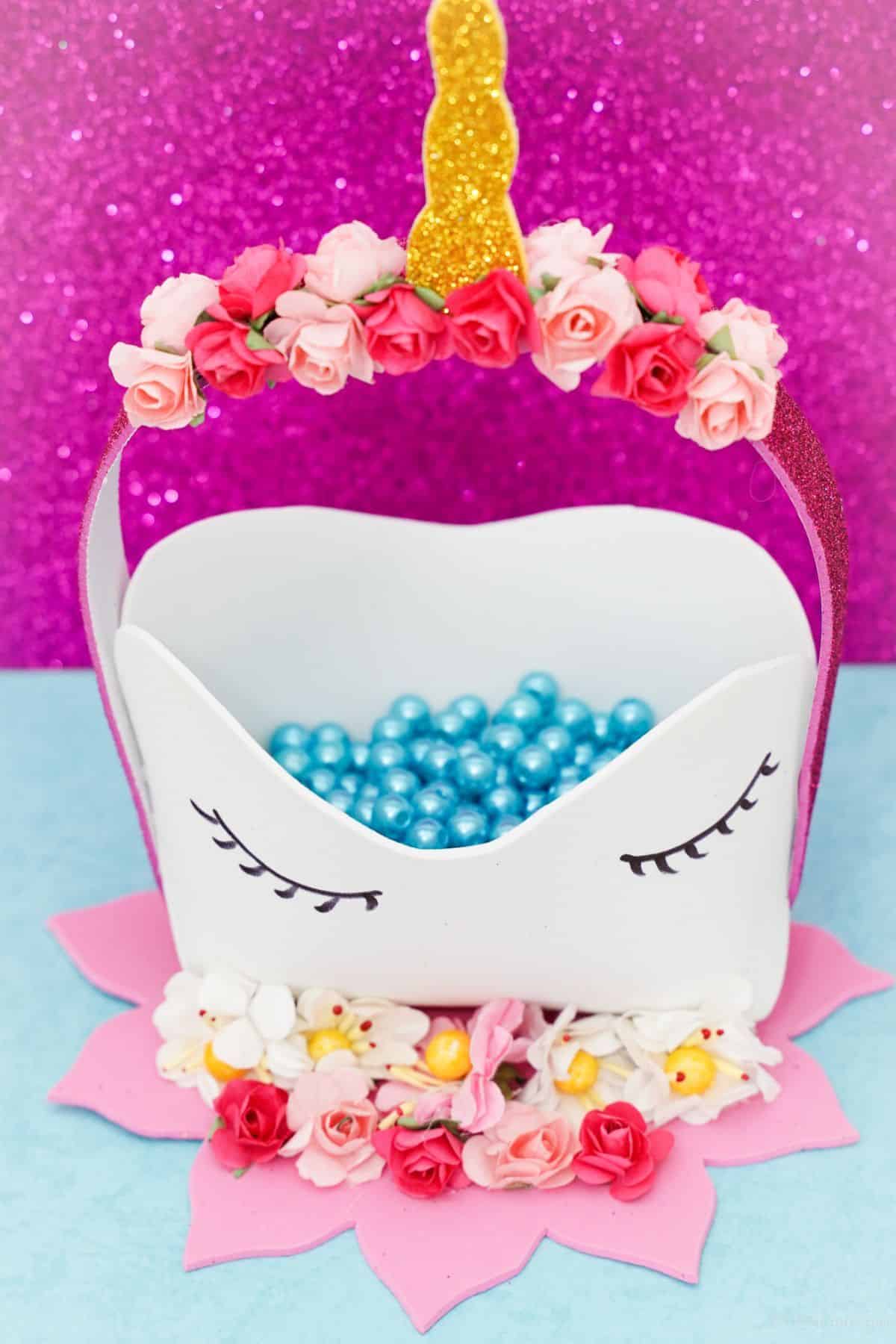 white and pink unicorn basket on a blue table with pink glitter background