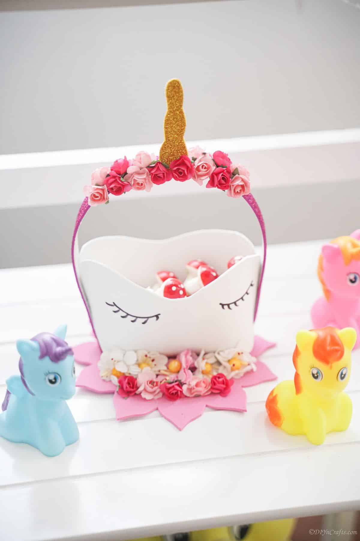 toy unicorns on shelf by paper unicorn basket