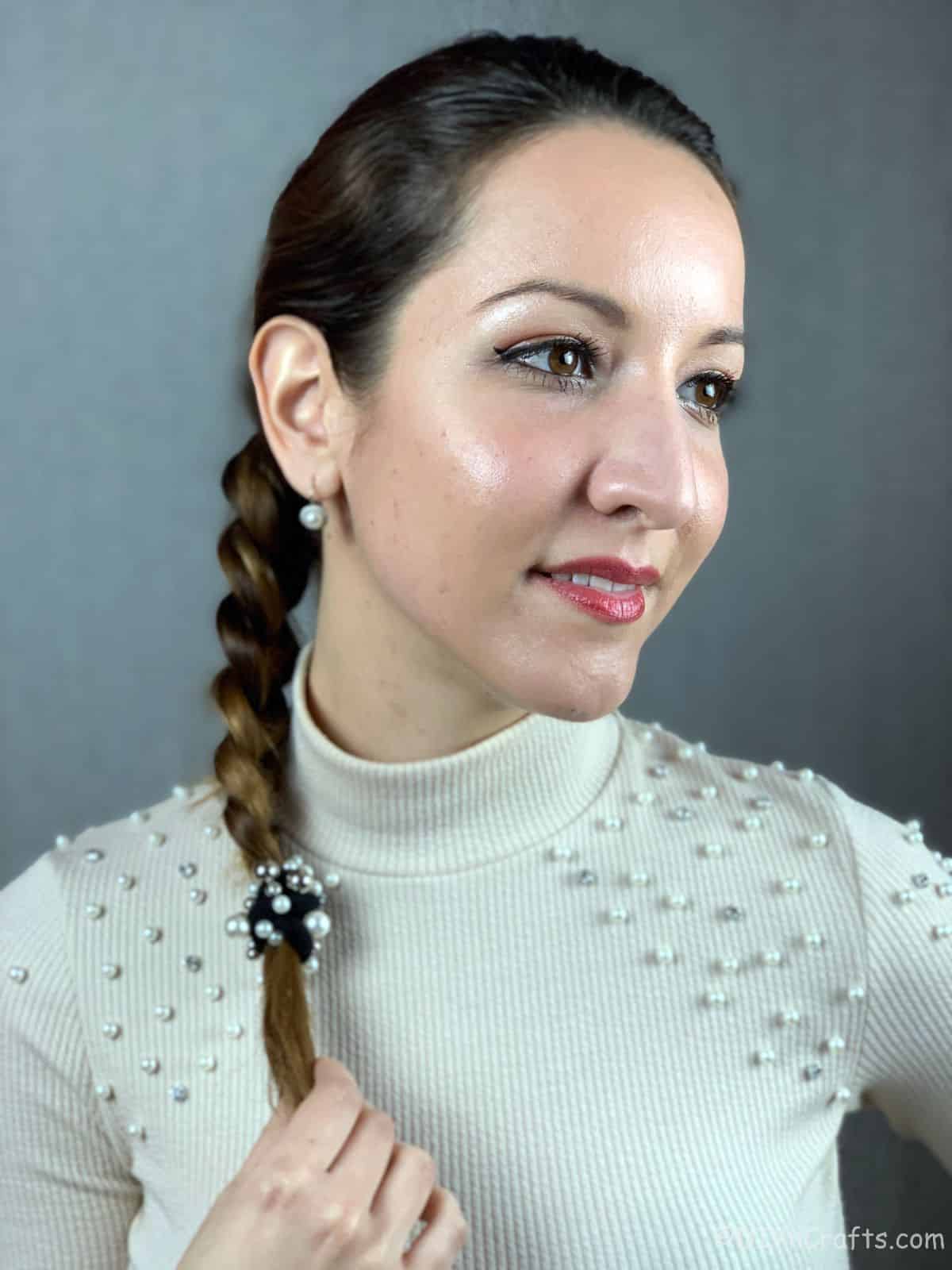 dutch braid hanging over shoulder of woman in white beaded sweater