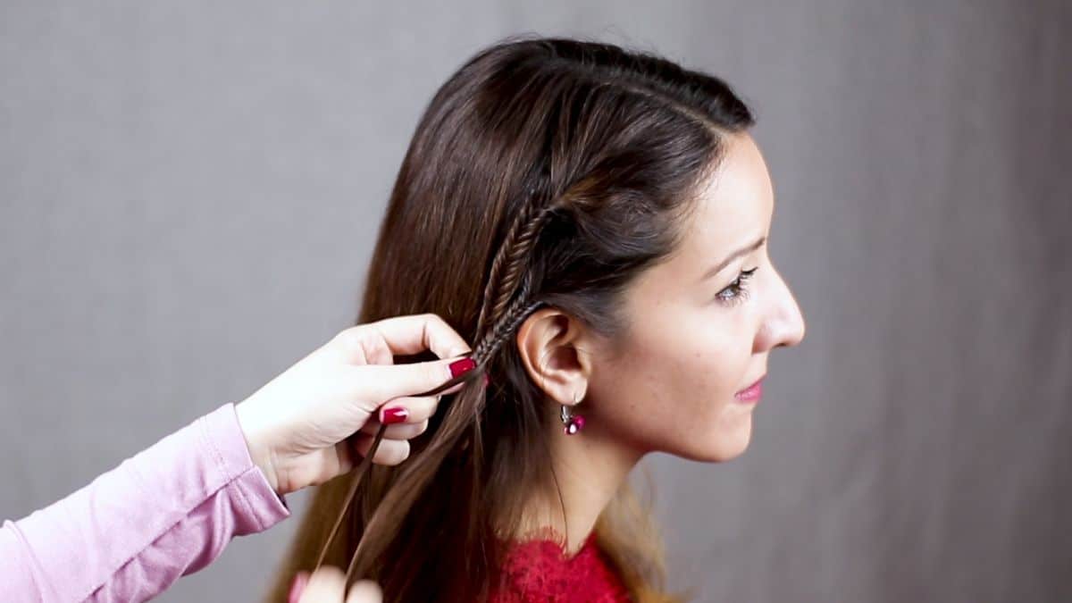 woman braiding small braids on side of head for woman in red shirt