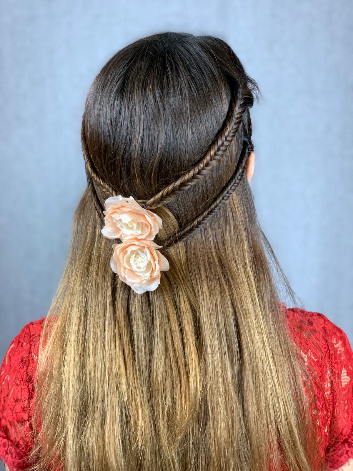 fishtail braids on side of hair with flower clip holding together in the back