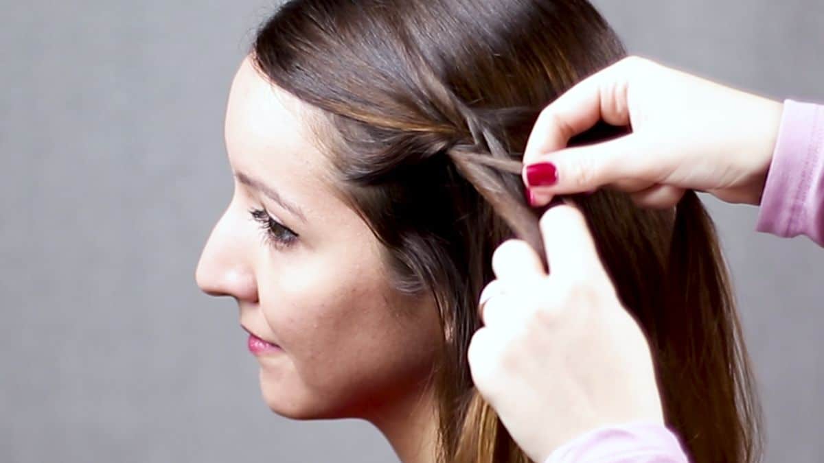 hand braiding small section of hair on side of brunettes head