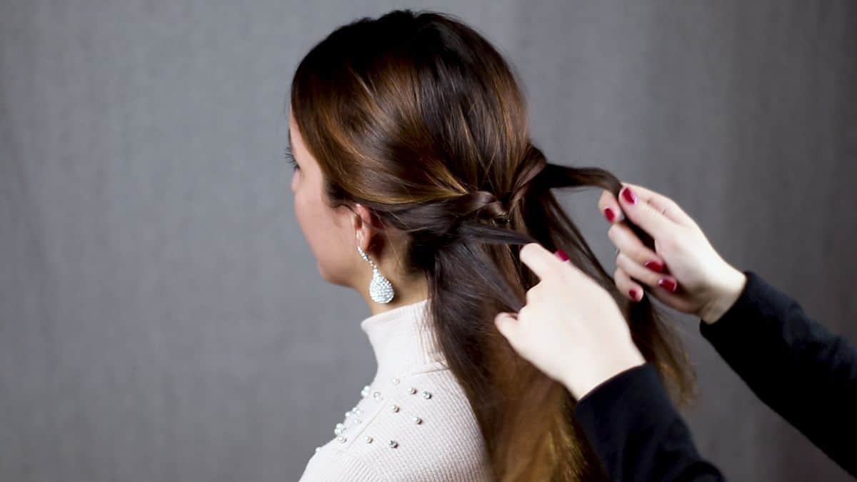 woman in black shirt twisting brunettes hair behind her head