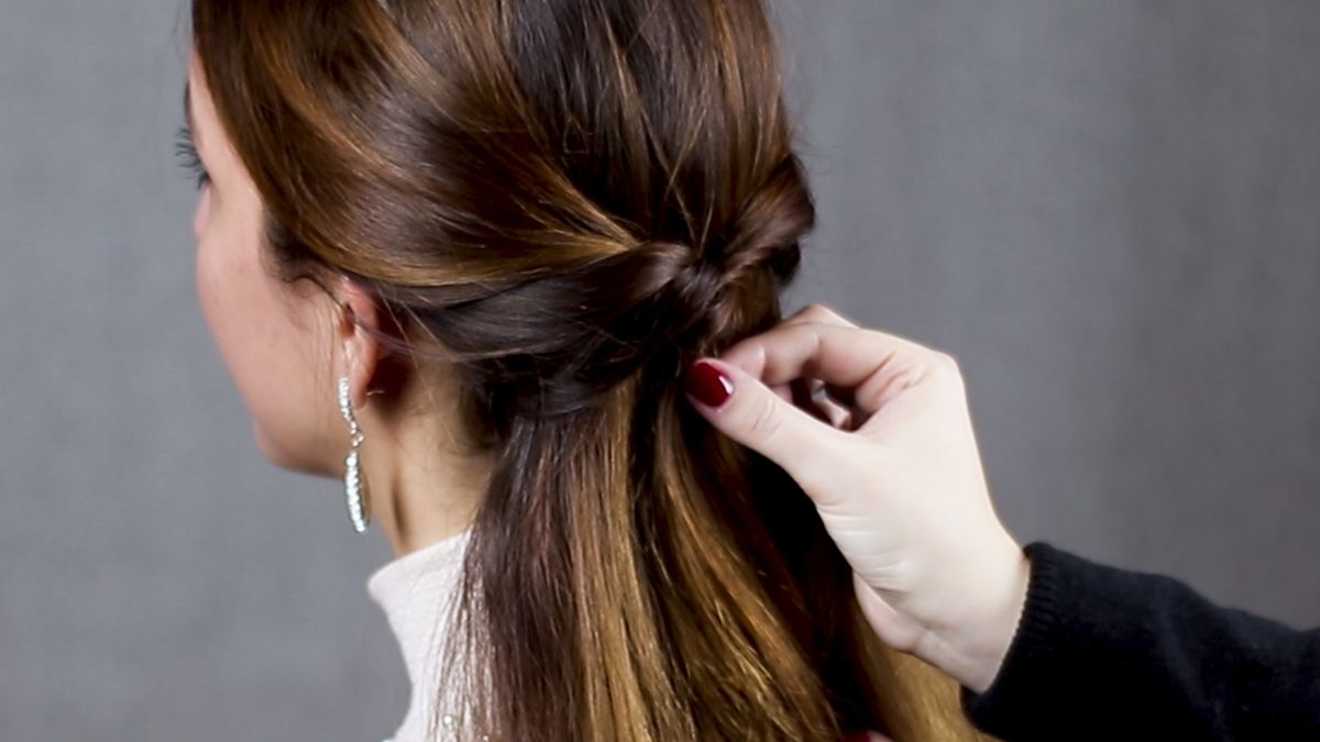hand with red nails straightening twist on back of brunettes head