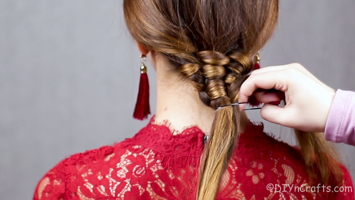 hair tie being wrapped around woven ponytail end