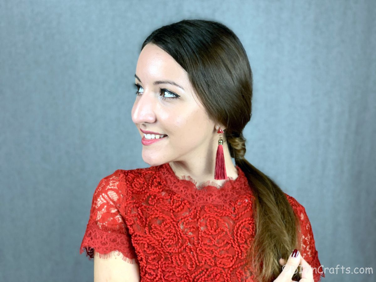red tassel earrings on woman with brown hair in low ponytail