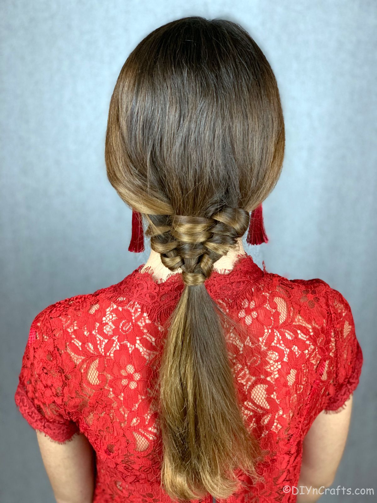 back of woven ponytail on brunette in red lace shirt