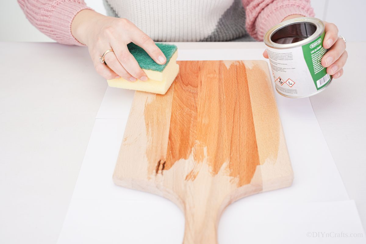 hand spreading stain on a cutting board