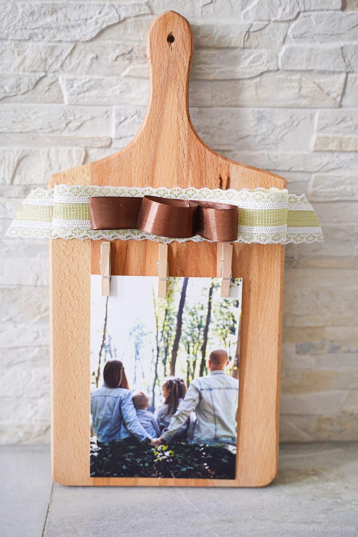 cutting board photo stand leaning against white brick wall