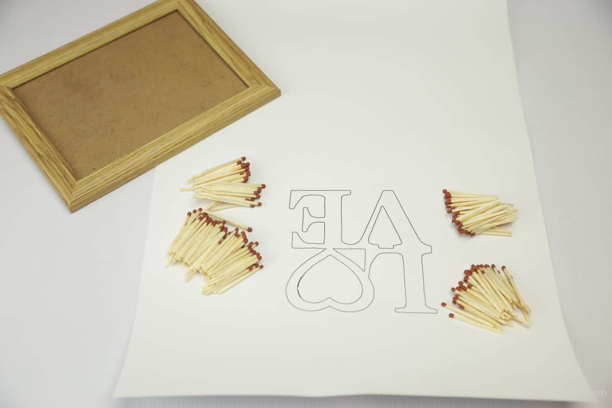 נייר מודפס עם מילים אהבה על שולחן עם מסגרת תמונה וגפרורים