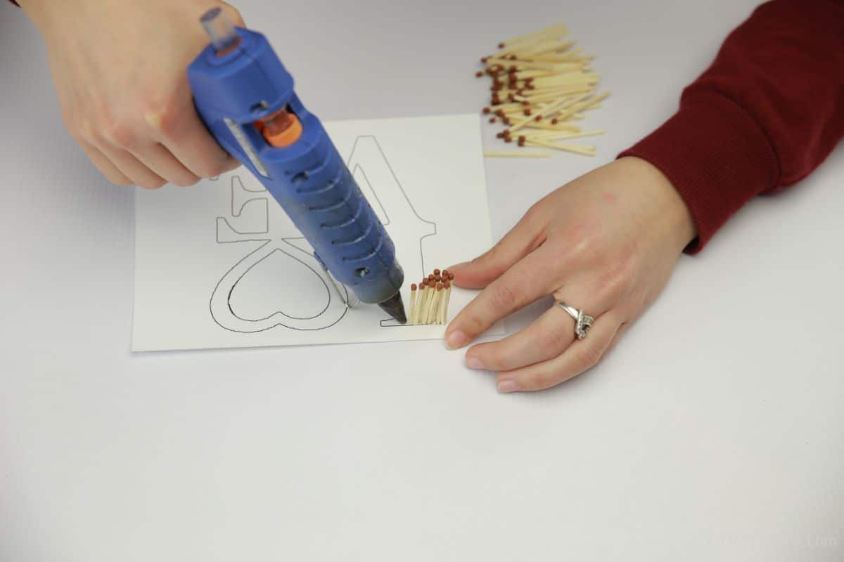 blue glue gun being used to attach matches to paper