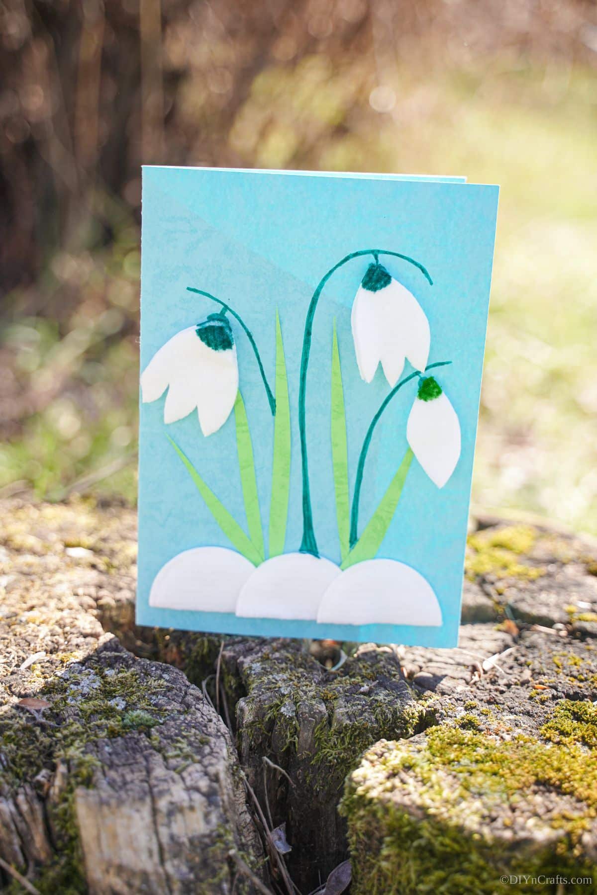 blue and green handmade card with flowers sitting on stump