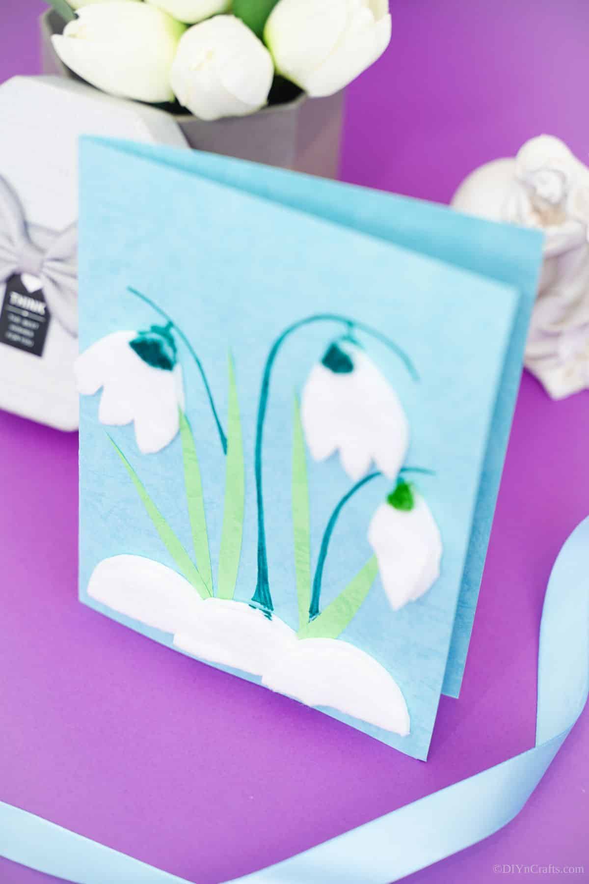 blue and white card with tulips sitting on purple surface