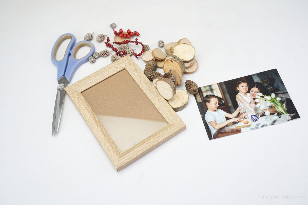 picture frame with wood slices and scissors on white table