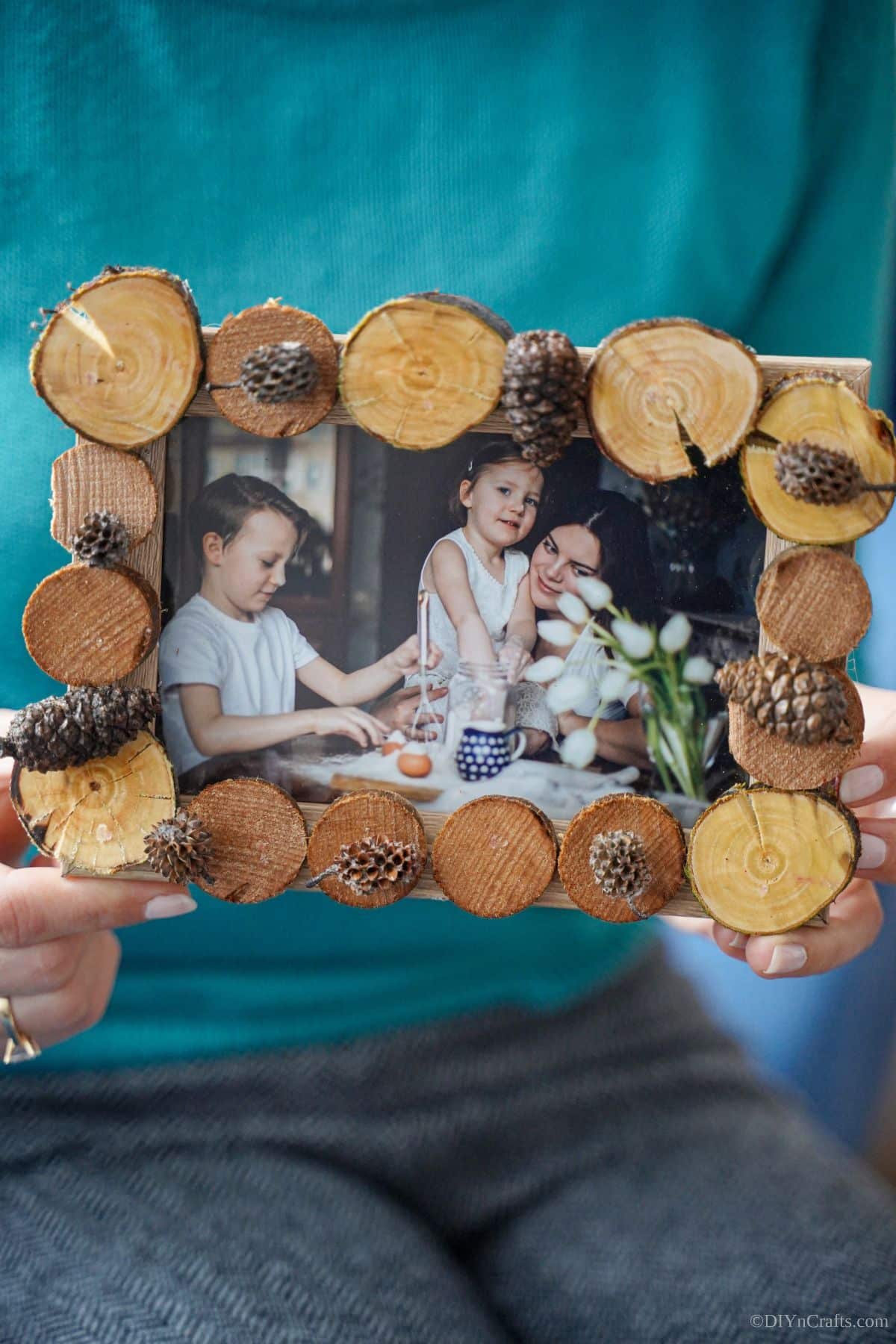 wood slice picture frame holding a family snapshot held by a woman wearing a blue sweater