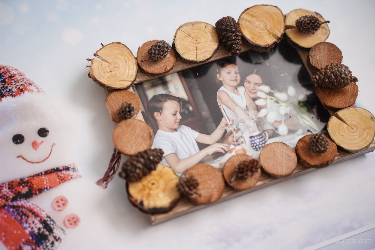 wood slice picture frame on white table by snowman