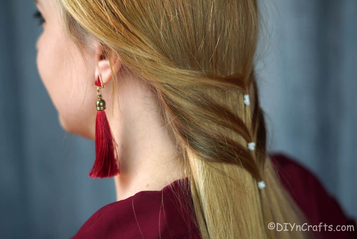 tassel earings and dark red shirt on woman with blonde hair
