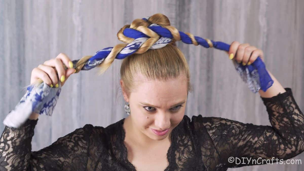 woman wrapping hair into bun with scarf