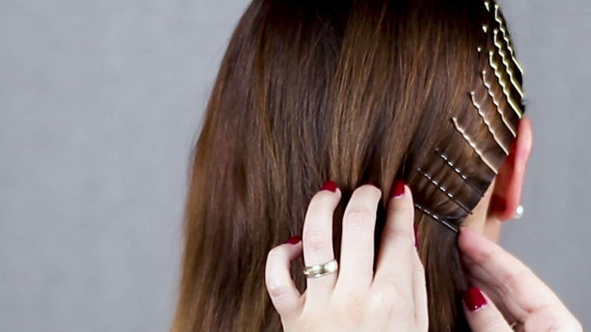 hand with red nails adding bobby pin to brown hair