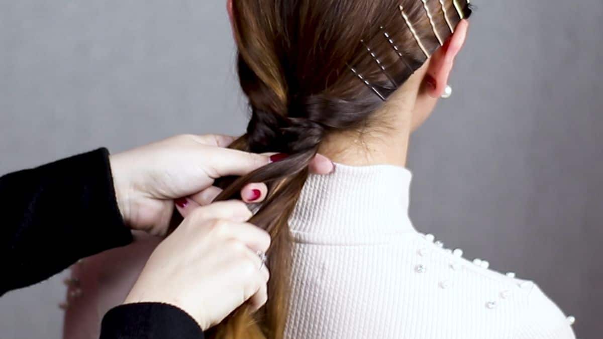 bobby pins against scalp while hand with red nails braids