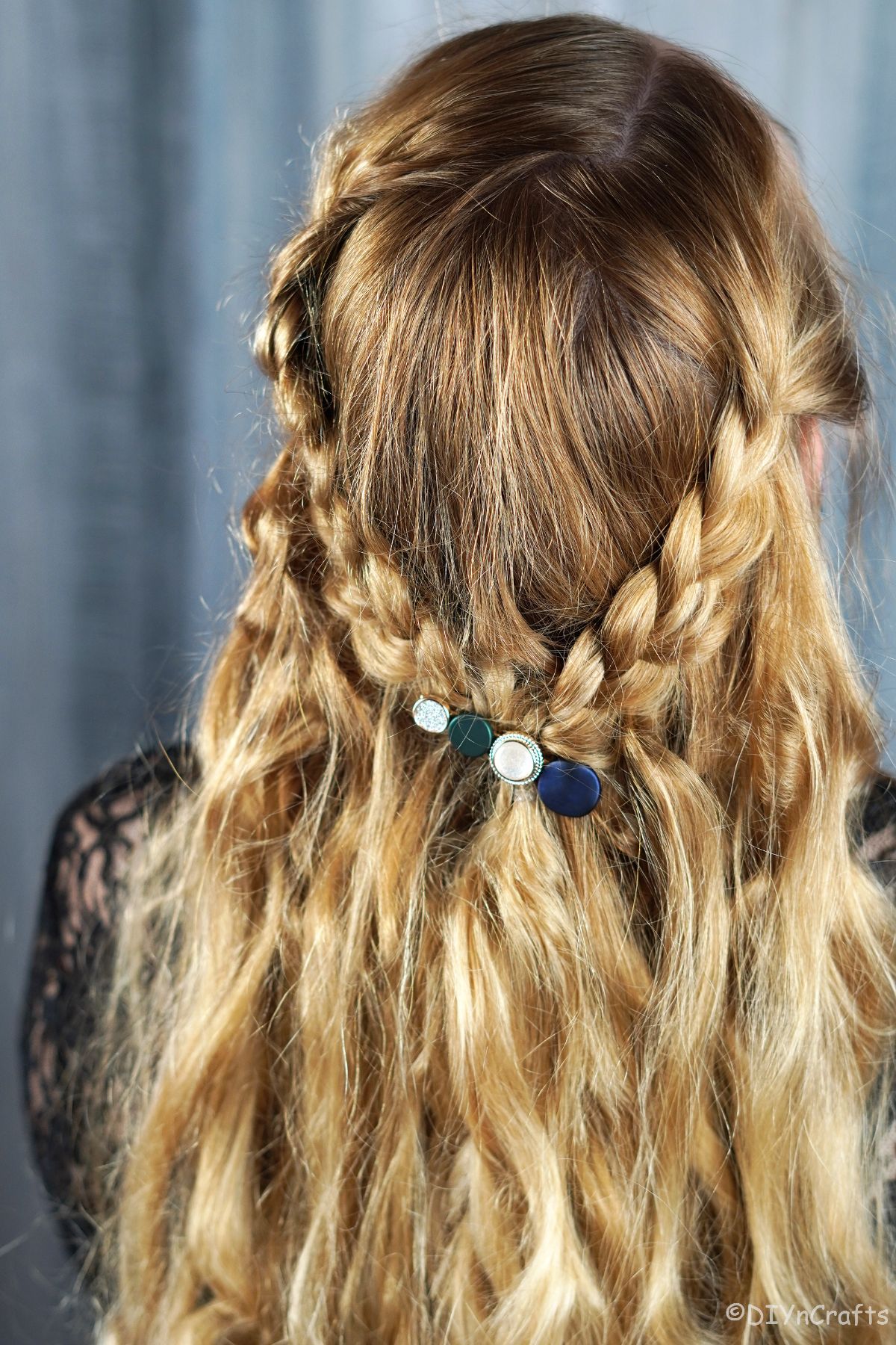 back of blonde hair with braids and decorative pin on half up hairstyle