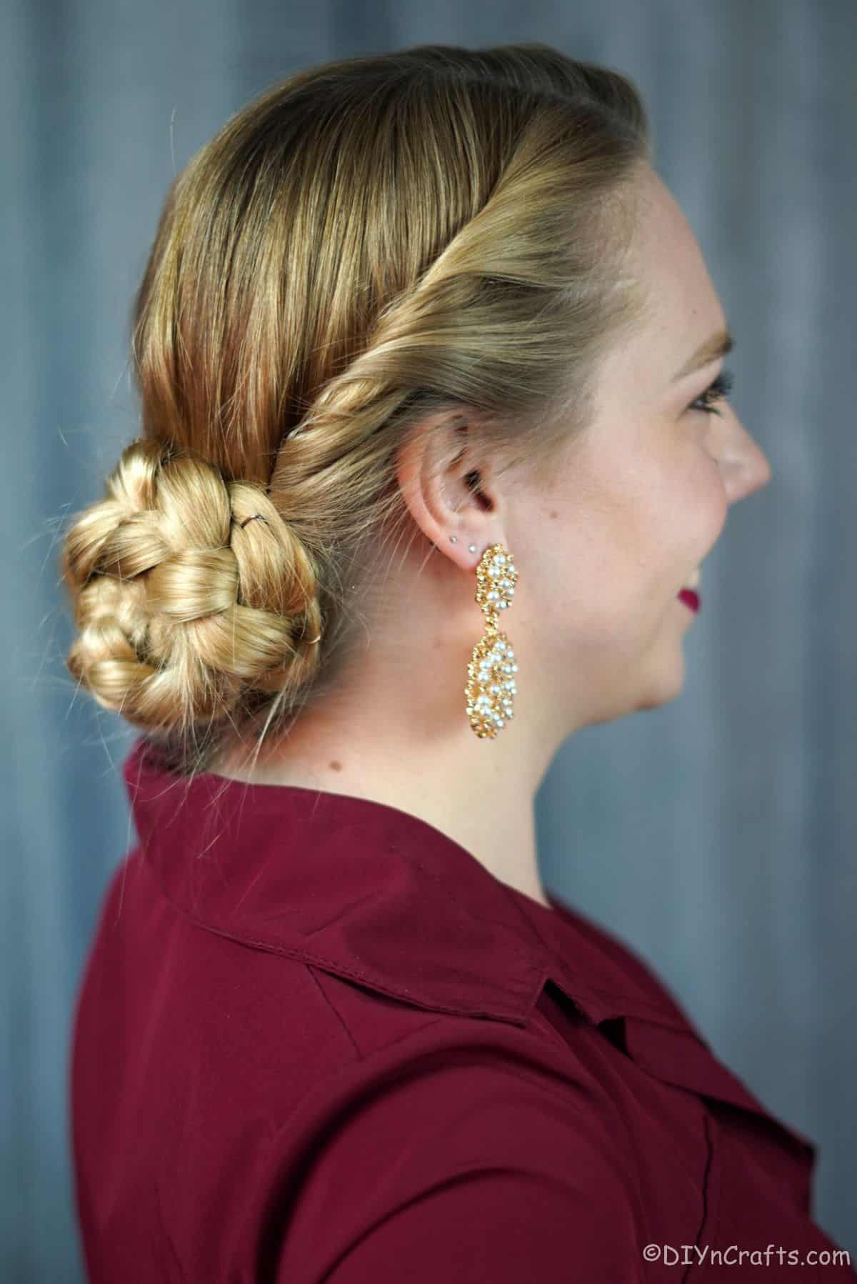 twisted braided low bun on blonde haired woman in maroon shirt